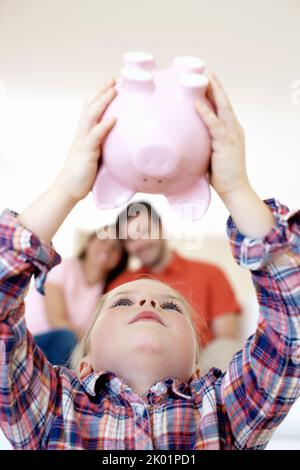 Wie viel ist hier enthalten. Ein kleines Mädchen hält ihren Huckepack auf den Kopf. Stockfoto