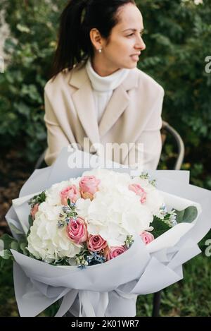 Frau hält Blumen großen Strauß weißen Hortensien Blumen und rosa Rosen. Blühende Blumen festlichen Hintergrund, Pastell und weichen Blumenstrauß Karte. Muttertag, Internationaler Frauentag. Stockfoto