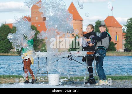 Fröhliche Kinder, die an einem sonnigen Tag mit Seifenblasen im Freien in der Nähe eines Schlosses spielen Stockfoto