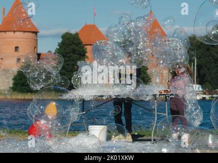 Fröhliche Kinder, die an einem sonnigen Tag mit Seifenblasen im Freien in der Nähe eines Schlosses spielen Stockfoto