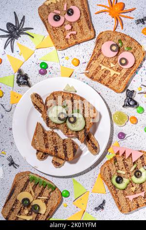Lustige halloween Monster Sandwiches. Set aus verschiedenen dekorierten Monster Sandwich und Toast, mit Gurken, Käse und Wurst, weißen Tisch Backgro Stockfoto