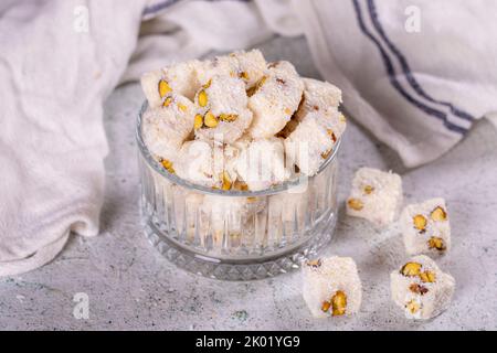 Türkische Freude mit Kokosnuss und Pistazie. Süßer türkischer Genuss auf grauem Hintergrund. Traditionelle türkische Delikatessen. Nahaufnahme Stockfoto