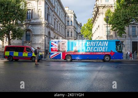 Ein Schwindel-Bus von Extinction Rebellion mit dem Aussehen eines Liz Truss-Kampagnenbusses vor der Downing Street. Slogan der Bürgerversammlung. Polizeiwagen Stockfoto
