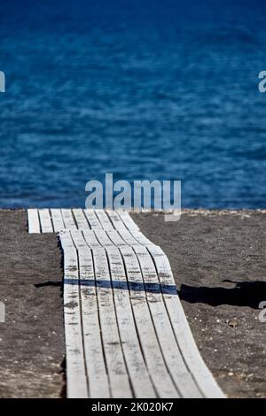 Perivilos Beach ist ein berühmter Ort für Hochzeitsempfänge und das kosmopolitischste und lebhafteste Strandresort in Santorini, das aus schwarzem Lavasand besteht. Stockfoto