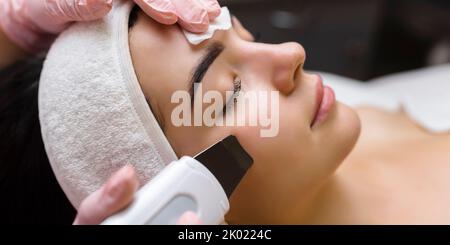 Gesichtsreinigung mit Ultraschall-Scrubber. Frau erhält Ultraschall-Gesichtspeeling und -Reinigung. Kosmetik- und Gesichtspflege. Gesichtsbehandlung Stockfoto