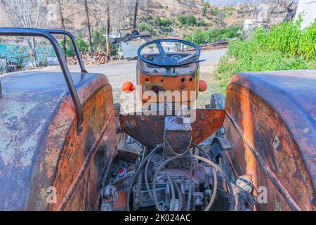 Alte rote Oldtimer-Traktor mit offenem Fahrerhaus. Foto eines ländlichen Traktors ohne Fahrerhaus. Nahaufnahme der Vorderseite des Traktors: Kühler, Scheinwerfer. Stockfoto
