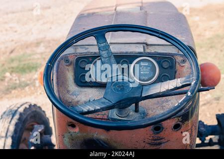 Alte rote Oldtimer-Traktor mit offenem Fahrerhaus. Foto eines ländlichen Traktors ohne Fahrerhaus. Nahaufnahme der Vorderseite des Traktors: Kühler, Scheinwerfer. Stockfoto