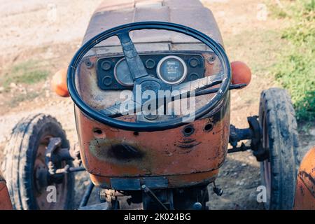 Alte rote Oldtimer-Traktor mit offenem Fahrerhaus. Foto eines ländlichen Traktors ohne Fahrerhaus. Nahaufnahme der Vorderseite des Traktors: Kühler, Scheinwerfer. Stockfoto