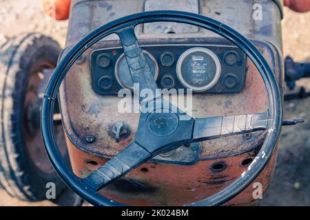 Alte rote Oldtimer-Traktor mit offenem Fahrerhaus. Foto eines ländlichen Traktors ohne Fahrerhaus. Nahaufnahme der Vorderseite des Traktors: Kühler, Scheinwerfer. Stockfoto