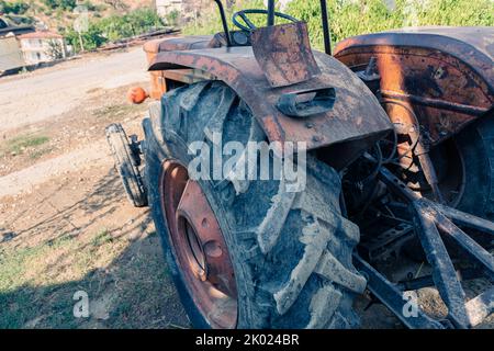Alte rote Oldtimer-Traktor mit offenem Fahrerhaus. Foto eines ländlichen Traktors ohne Fahrerhaus. Nahaufnahme der Vorderseite des Traktors: Kühler, Scheinwerfer. Stockfoto