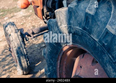 Alte rote Oldtimer-Traktor mit offenem Fahrerhaus. Foto eines ländlichen Traktors ohne Fahrerhaus. Nahaufnahme der Vorderseite des Traktors: Kühler, Scheinwerfer. Stockfoto