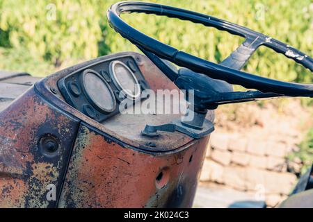 Alte rote Oldtimer-Traktor mit offenem Fahrerhaus. Foto eines ländlichen Traktors ohne Fahrerhaus. Nahaufnahme der Vorderseite des Traktors: Kühler, Scheinwerfer. Stockfoto