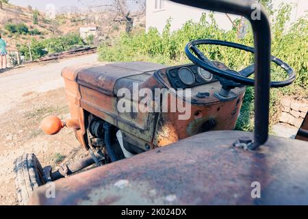 Alte rote Oldtimer-Traktor mit offenem Fahrerhaus. Foto eines ländlichen Traktors ohne Fahrerhaus. Nahaufnahme der Vorderseite des Traktors: Kühler, Scheinwerfer. Stockfoto