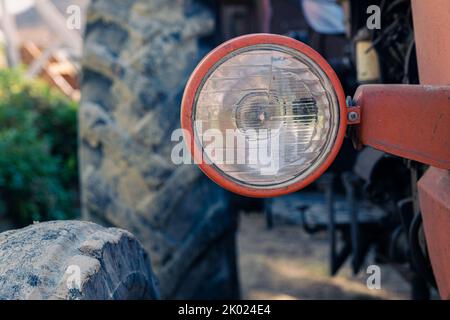 Alte rote Oldtimer-Traktor mit offenem Fahrerhaus. Foto eines ländlichen Traktors ohne Fahrerhaus. Nahaufnahme der Vorderseite des Traktors: Kühler, Scheinwerfer. Stockfoto