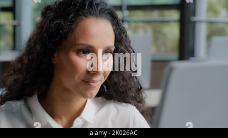 Fokussierte seriöse Frau, die im Büro am Computer arbeitet und dabei die Nahaufnahme eines Monitors betrachtet, eine nachdenkliche weibliche Berufsarbeiterin, die Informationen liest, um neue zu entwickeln Stockfoto