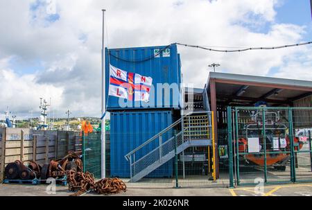 RNLI Royal National Lifeboat Institution Fahne bei der Hälfte des Personals als Zeichen des Respekts oder der Erinnerung. Stockfoto