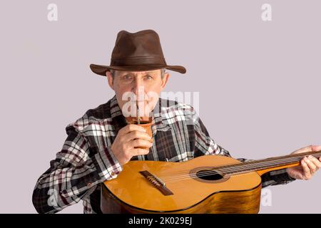 Alter Mann mit Gitarre und der typischen Infusion in Argentinien und Uruguay namens Mate Stockfoto