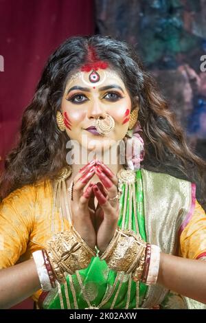 Schöne indische Frau, die als Hindu-Göttin Durga gekleidet ist und von der Kamera wegschaut. Dies ist ein repräsentatives Konzept von Agomoni Stockfoto