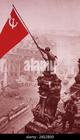 *Coloriert* am 30. April 1945 wurde das scharlachrote Siegesbanner über dem brennenden Reichstag in Berlin gehisst. Am 8. Mai wurde der Akt der bedingungslosen Kapitulation des faschistischen Deutschlands unterzeichnet. Die sowjetische Armee rettete die Völker Europas vor der faschistischen Sklaverei. Stockfoto