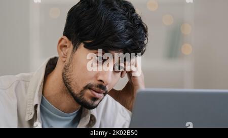 Frontansicht männlich fokussiert arabisch junger Mann Geschäftsmann Freiberufler Blick auf Laptop müde Beschwerden in den Augen Schmerzen beunruhigendes Problem schlechte Nachrichten hebt ab Stockfoto