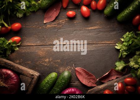 Hintergrund Gemüse Herbsternte. Tomaten und Gurken mit Herbstlaub rustikalen Hintergrund Kopieplatz. Stockfoto