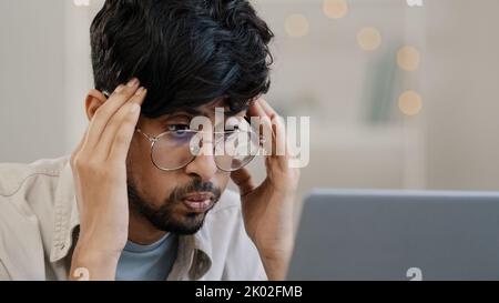 Krank arabischer Geschäftsmann Student männlich bärtig Chef Führer mit Brille Kerl arbeitet mit Laptop Probleme leidet an Kopfschmerzen Massagen Kopf Gefühl Stress Stockfoto