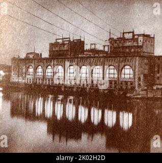 Das Flaggschiff der sowjetischen elektrischen Energie, Wolhowskaja Wasserkraftwerk. Das Wasserkraftwerk Volkhov ist ein Wasserkraftwerk am Fluss Volkhov in der Stadt Volkhov, im Gebiet Leningrad, im Nordwesten Russlands. Es ist das älteste und am längsten in Betrieb befindliche Wasserkraftwerk in der Sowjetunion und Russland. Die Bauarbeiten begannen im Jahr 1918. Am 16. September 1921 wurde es in einen GOELRO-Plan aufgenommen. Genrikh Graftio, einer der Gründer des Plans, war für den Bau des Bahnhofs verantwortlich. Die Anlage wurde 1927 mit einer Leistung von 6.000 Kilowatt fertiggestellt. Stockfoto