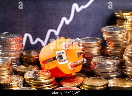 Steigende Stromkosten, Steckdosen mit Geldstapeln und Grafik mit steigender Kurve. Stockfoto