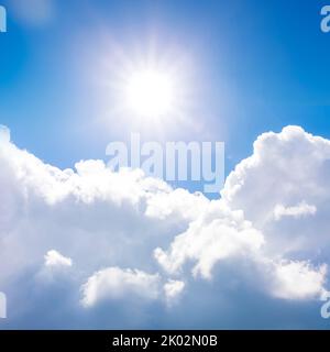 Sonne gegen blauen Himmel und weiße Kumuluswolken Stockfoto