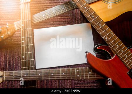 Die gestapelten Gitarren und Blatt Papier setzen den Text.Copy Raum Stockfoto