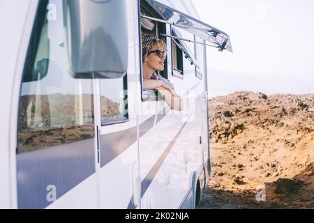 Sommerurlaub Urlaub Urlaub mit Vermietung Wohnmobil Wohnmobil Wohnmobil. Glückliche Frau, die vor dem Fenster die Natur bewundert. Landschaftlich reizvolle Destination Vanlife Lifestyle. Tourist, der die Ankunft am Strand genießt Stockfoto