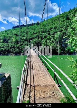 Eine vertikale Aufnahme einer kleinen hölzernen Fußgängerbrücke über einen Fluss Stockfoto