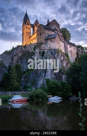 Deutschland, Hessen, Mittelhessen, Limburg-Weilburg, Dietkirchen, St. Lubentius Basilika bei Limburg und der Lahn zur blauen Stunde im Sommer, mit Booten auf der Lahn im Vordergrund Stockfoto