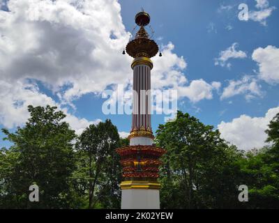 Die Phra That Sri Surat Säule in Surat Thani, Thailand gegen bewölkten Himmel und Grün Stockfoto