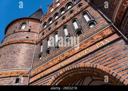 Das Holstentor ist das Wahrzeichen der Stadt und neben dem Burgtor das einzige erhaltene Stadttor Lübecks. In den Räumen des Holstentors befindet sich seit 1950 das Stadthistorische Museum. Das spätgotische Gebäude ist Teil der ehemaligen Lübecker Stadtbefestigung. Inschrift auf der Felsseite des Holsten-Tores. 'Concordia domi foris pax' 'Eintracht im Inneren und Frieden im Freien'. Stockfoto