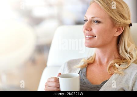 Beginnen Sie den Tag mit einer Tasse joe. Eine Frau, die zu Hause eine Tasse Kaffee genießt. Stockfoto