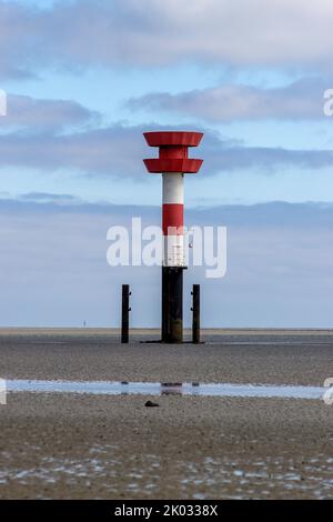 Eine vertikale Aufnahme eines Leuchtfeuers im Wattenmeer bei Ebbe. Stockfoto