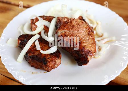 Schweinehals-Kebabs mit Zwiebeln auf weißem Teller im Restaurant Stockfoto