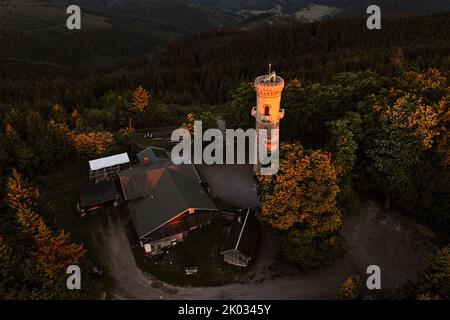 Deutschland, Thüringen, Ilmenau, erste Morgensonnenstrahlen erleuchten wie ein Scheinwerfer den Beobachtungsturm am Kickelhahn, Wald, Übersicht, Luftaufnahme Stockfoto