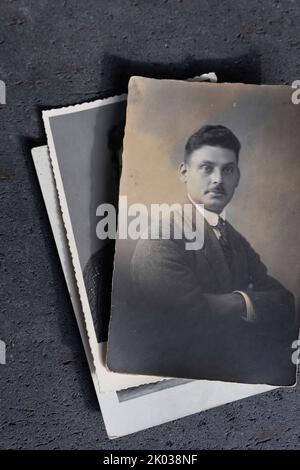 Portraitfoto eines Mannes auf einem Stapel vergilbter Fotos Stockfoto