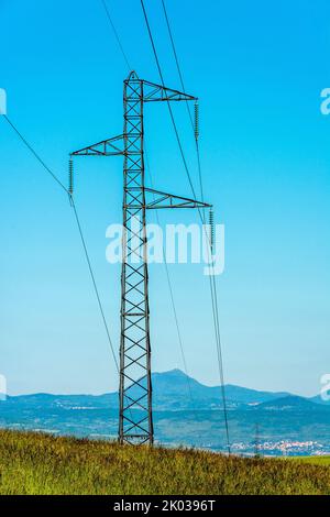 Hochspannungsmast in einem Feld, im Hintergrund der vulkan puy de Dome, Puy de Dome, Auvergne Rhone Alpes, Frankreich Stockfoto