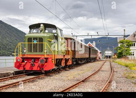 Norwegen, Vestfold Og Telemark, Rjukan, Mæl, Bahnhof, Zug auf Plattform stehend, Diesellokomotive, Teakholzwagen, Eisenbahnfähre Storgut (Hintergrund) Stockfoto