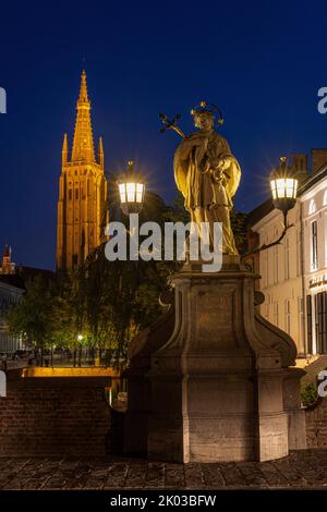 Statue des heiligen Johannes Nepomuk und Turm der Kirche unserer Lieben Frau in der Nacht. Brügge, Flandern, Belgien. Stockfoto
