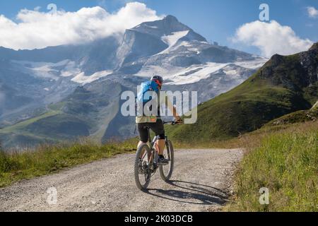 Österreich, Tirol, Tuxer Alpen. Ein Mann fährt mit einem E-Bike (emtb) bergauf zum Tuxerjoch, im Hintergrund der Hintertuxer Gletscher Stockfoto