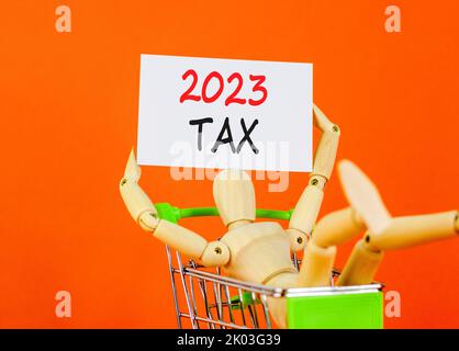 Symbol für 2023 Steuern für das neue Jahr. White Paper mit Worten 2023 Steuer, menschliches Modell in warenkorb. Schöne orange Tisch orange Hintergrund. Geschäft und 2023 Steuer ne Stockfoto
