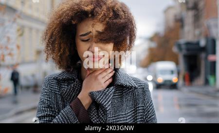Weibliche Porträt jung traurig lockig afroamerikanisch Mädchen Frau Gefühl Halsschmerzen Beschwerden Husten leiden an Grippe-Symptome von Coronavirus Asthma Stockfoto
