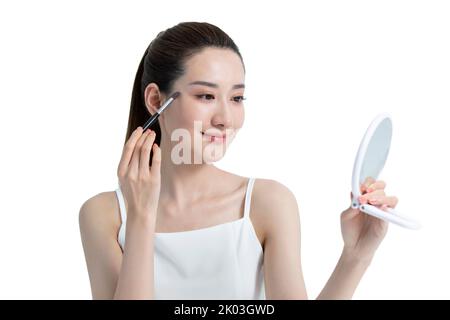 Schöne junge chinesische Frau, die Make-up anwendet Stockfoto