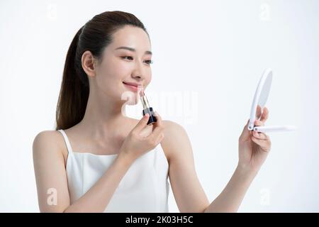 Schöne junge chinesische Frau, die Make-up anwendet Stockfoto