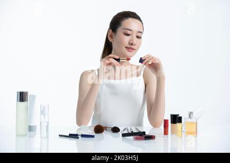Schöne junge chinesische Frau, die Make-up anwendet Stockfoto