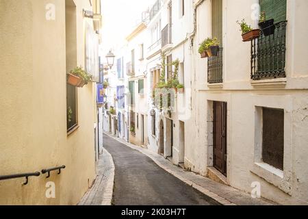 Blick auf eine kleine Straße mit weißen Häusern und Blumen in der traditionellen spanischen Stadt Sitges in Katalonien Stockfoto